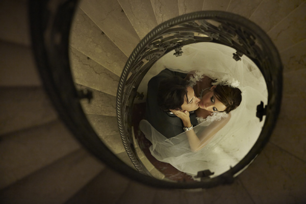 looking down circular staircase at bride and groom kissing - photo by destination wedding photographer Jerry Ghionis